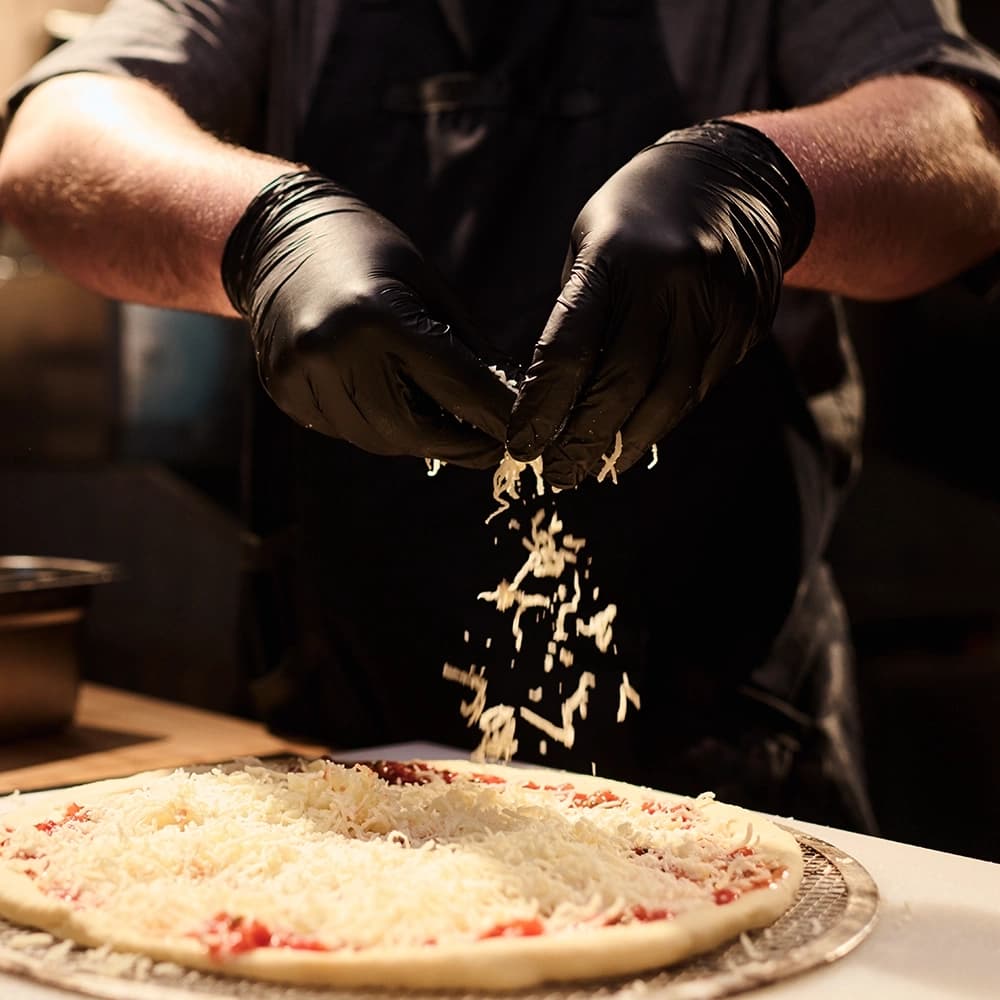 Close-up of artisan pizza dough being hand-stretched by experienced pizzaiolo
